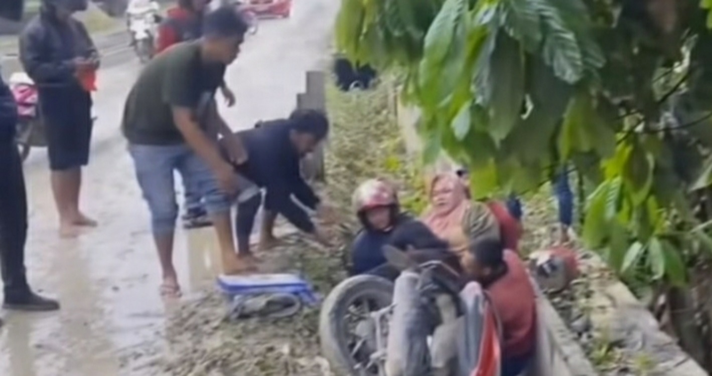Jalan Licin Diduga Akibat Ceceran Tanah, Emak-emak Pengendara Motor Nyungsep ke Drainase Jalan
